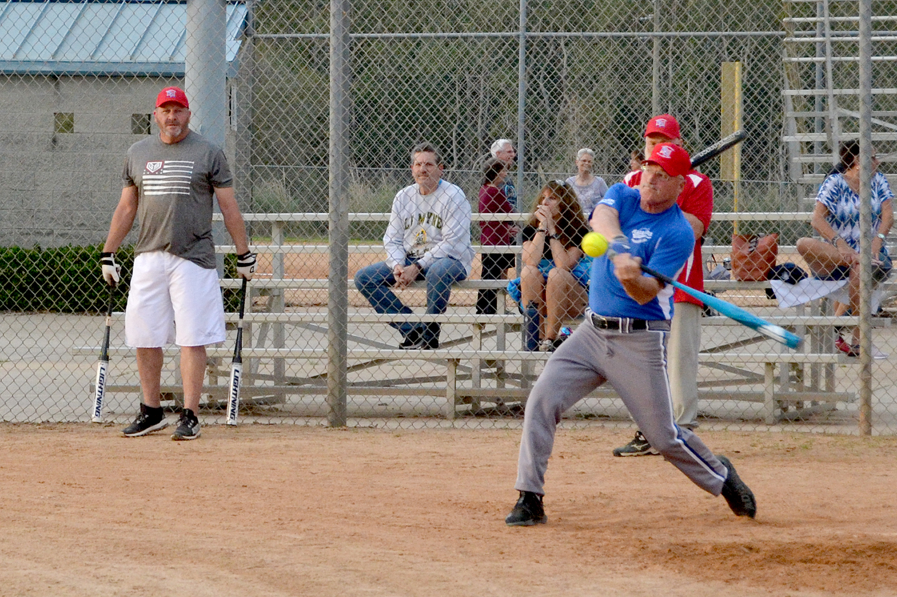 A batter swings during a senior softball event.
