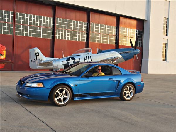 A Ford Mustang is placed in front of an antique plane for this publicity photo